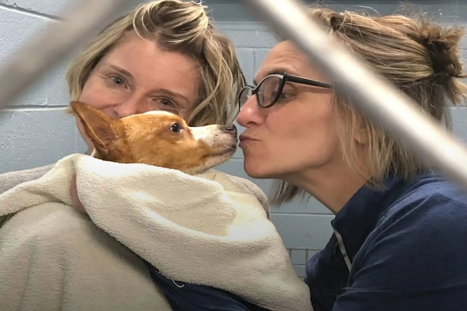 Dos mujeres abrazando y besando al perro que rescataron.