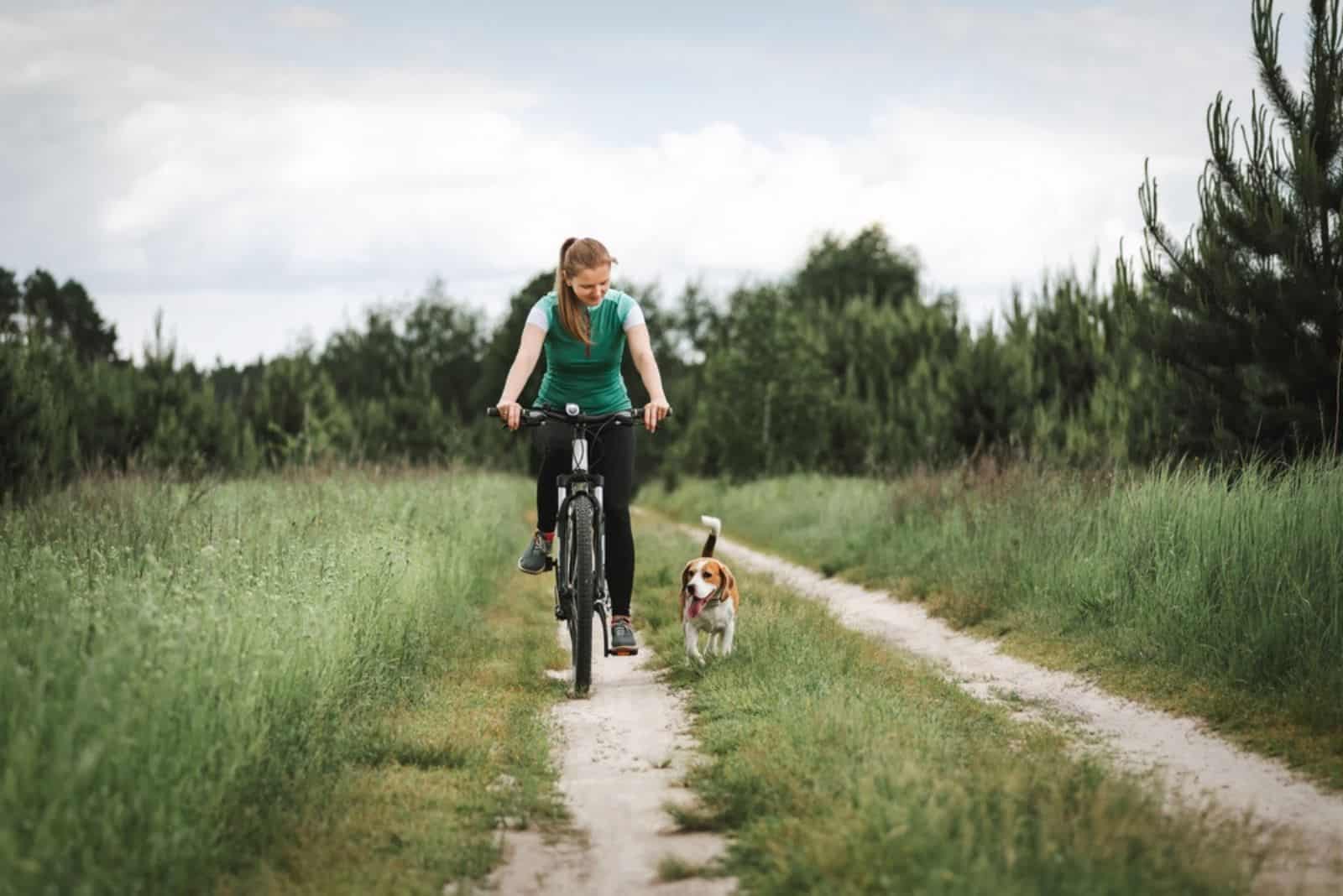 woman cycling with a dog in nature