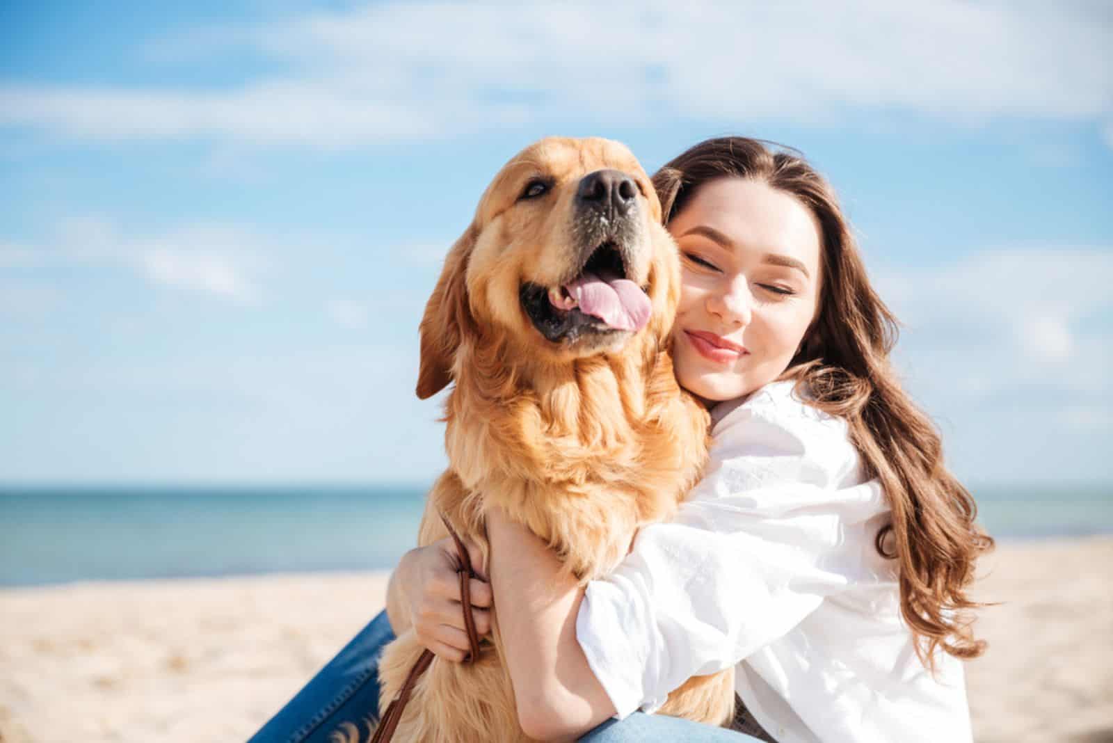 woman hugging her dog on the beach