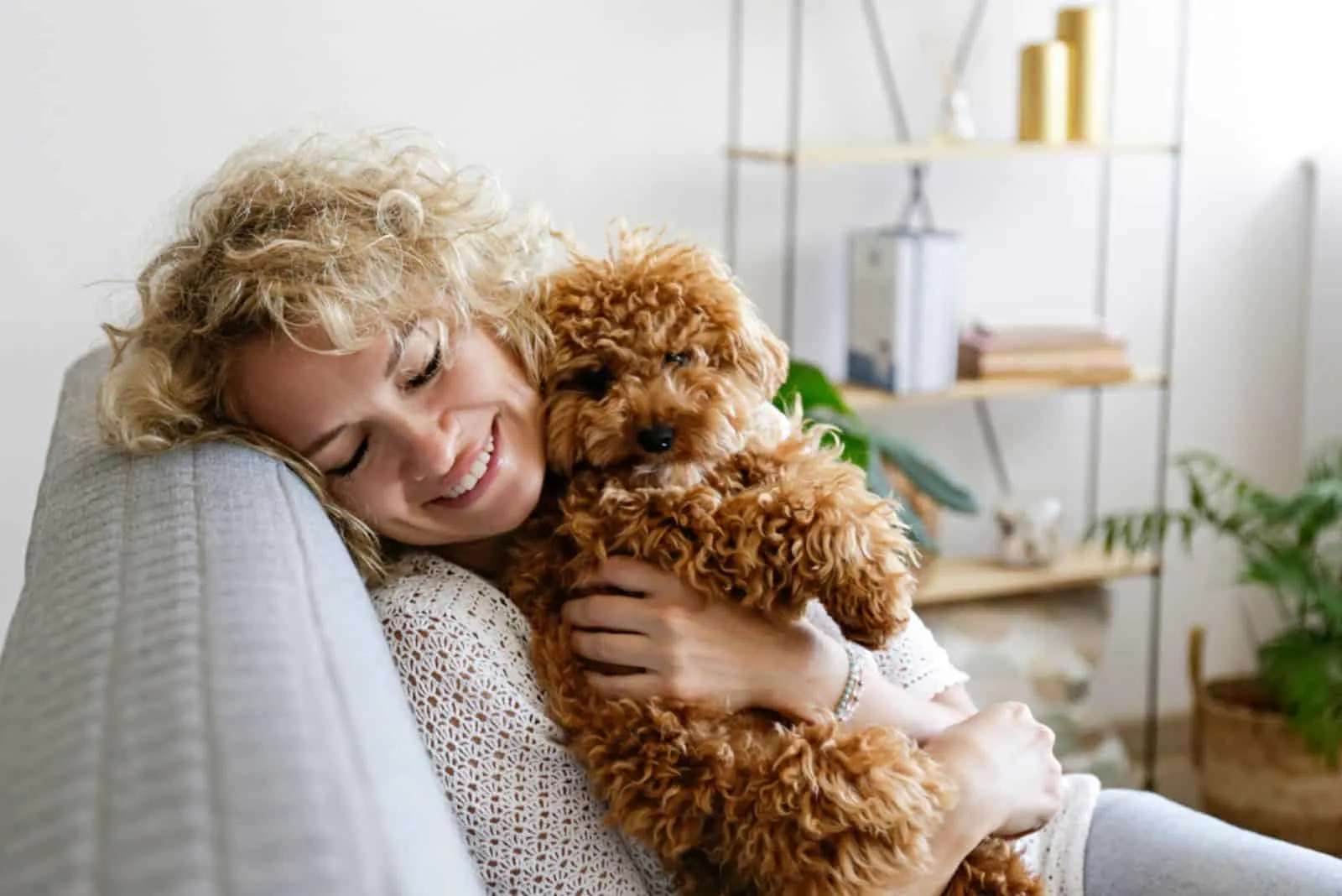 woman hugging her toy poodle dog on the couch