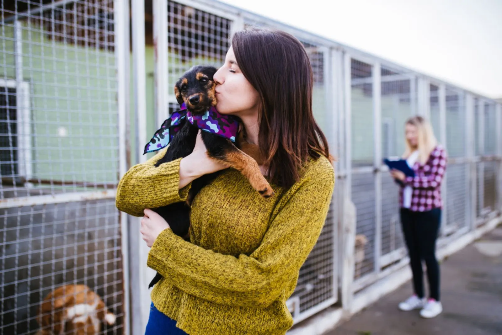 woman kissing a puppy in a shelter