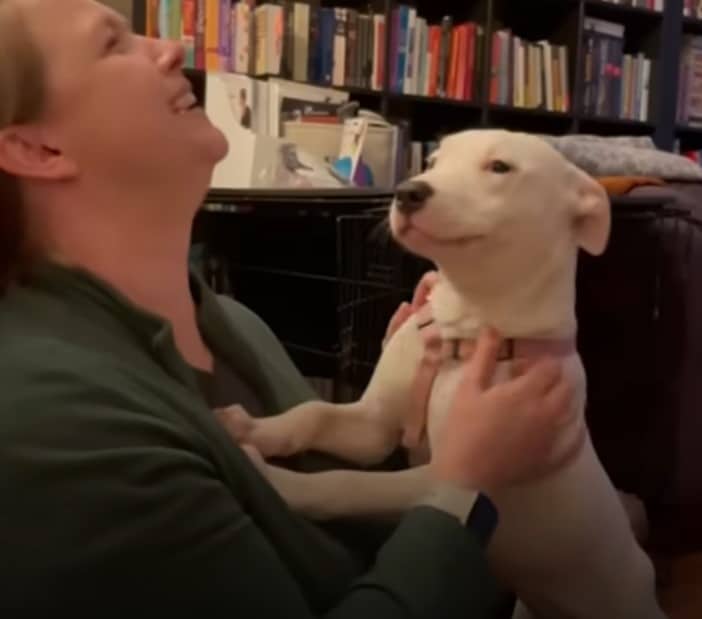 a smiling woman is playing with her dog