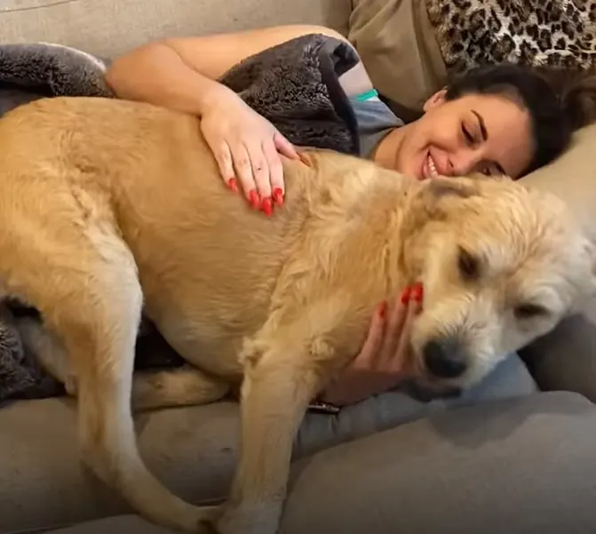 happy woman laying with dog on the couch