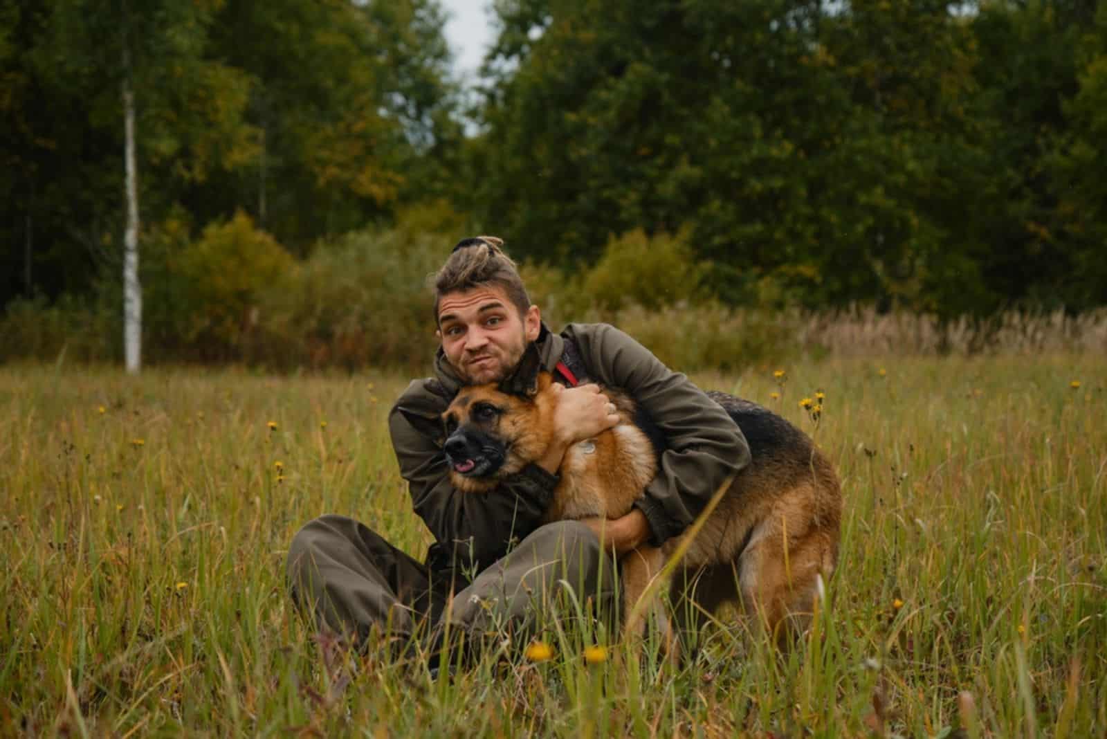 man hugging his german shepherd dog in nature