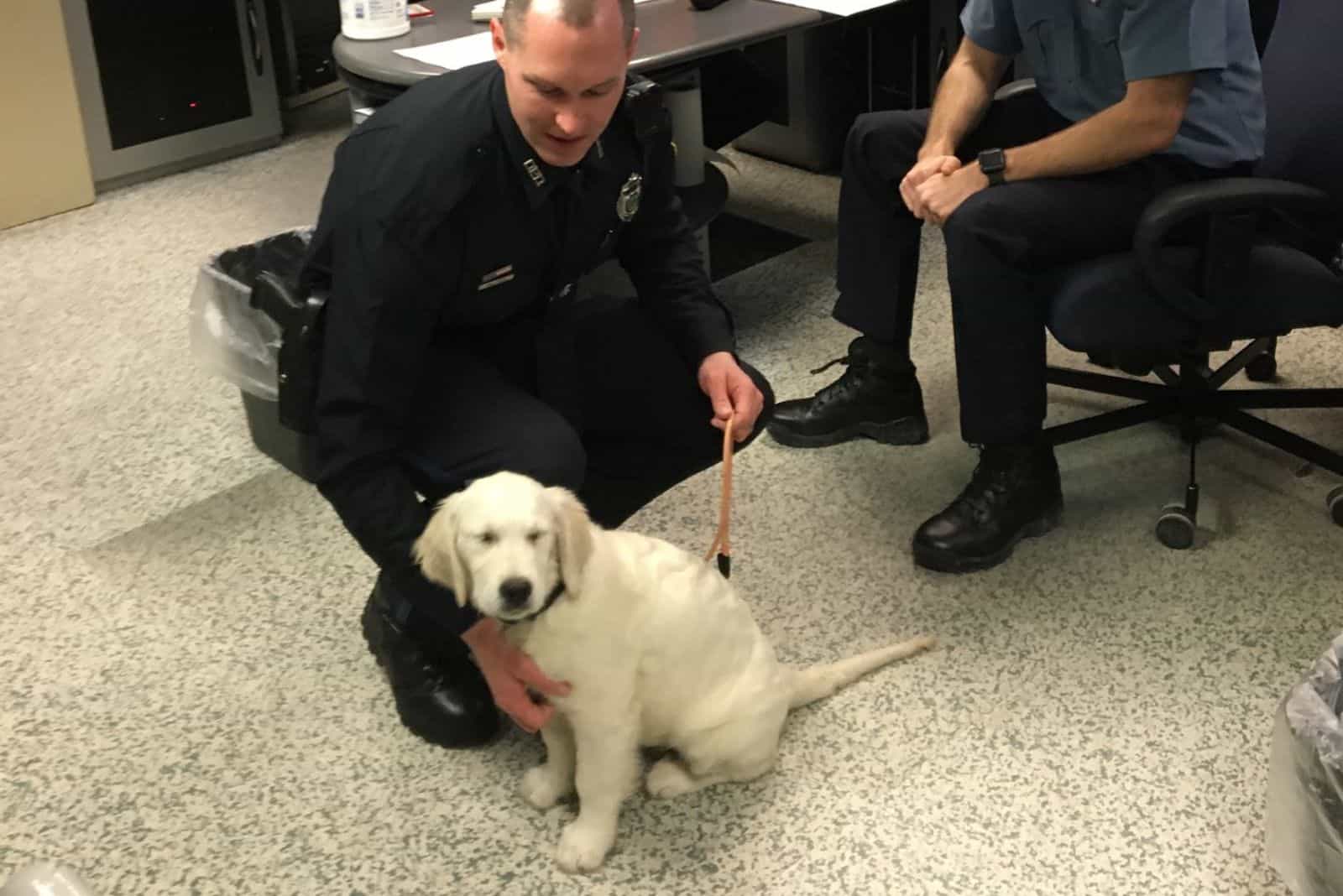 policeman cuddling white puppy in office
