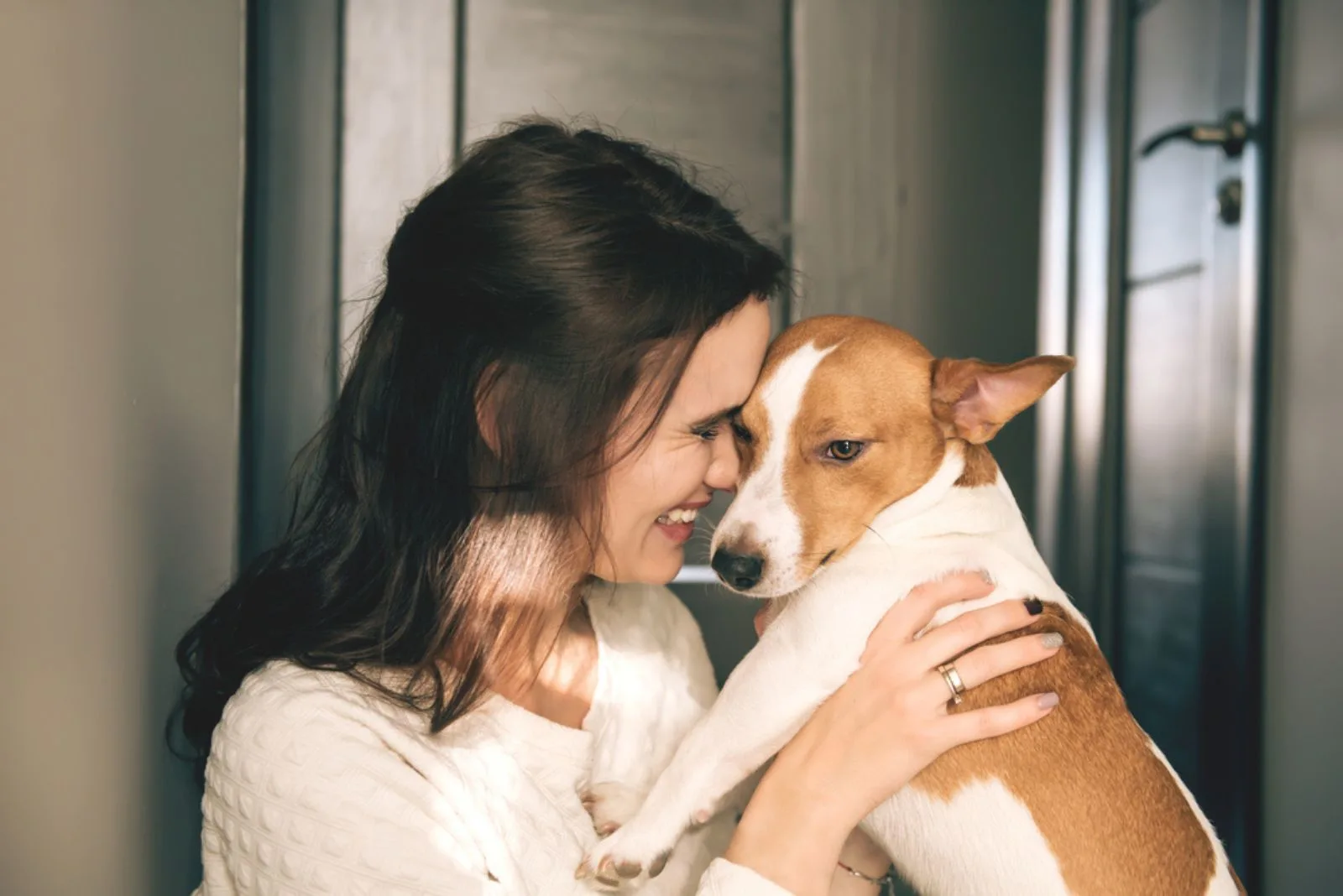 smiling woman hugging a dog at home