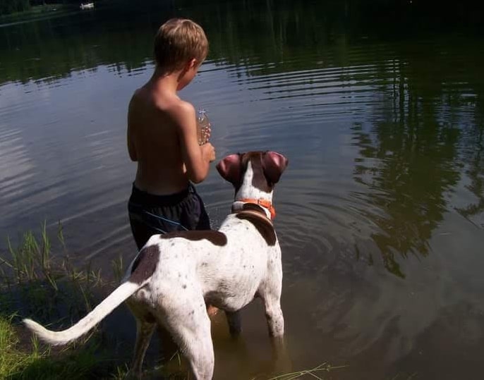 the boy and the dog are standing in the water
