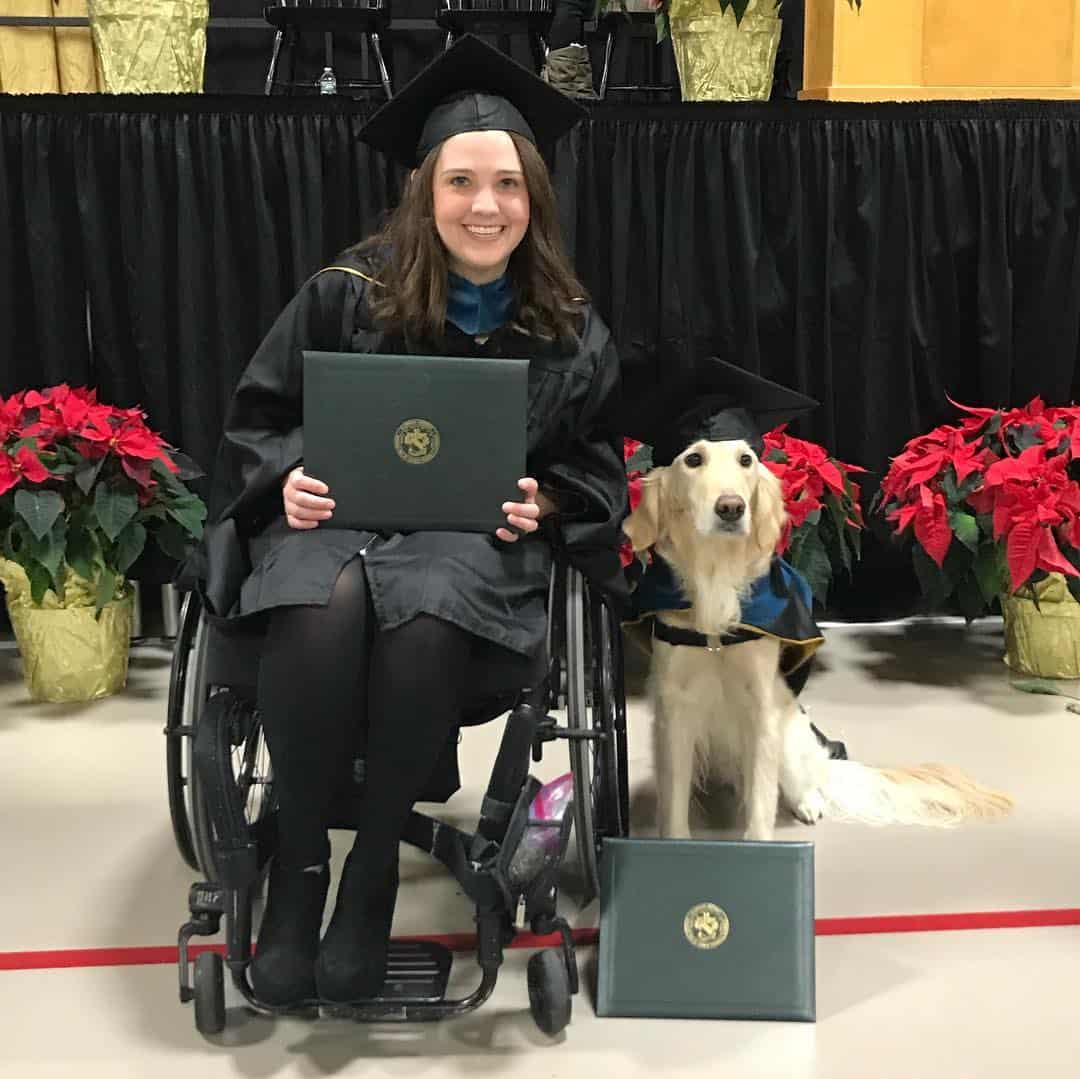 the dog stands next to the girl in the wheelchair at the graduation ceremony