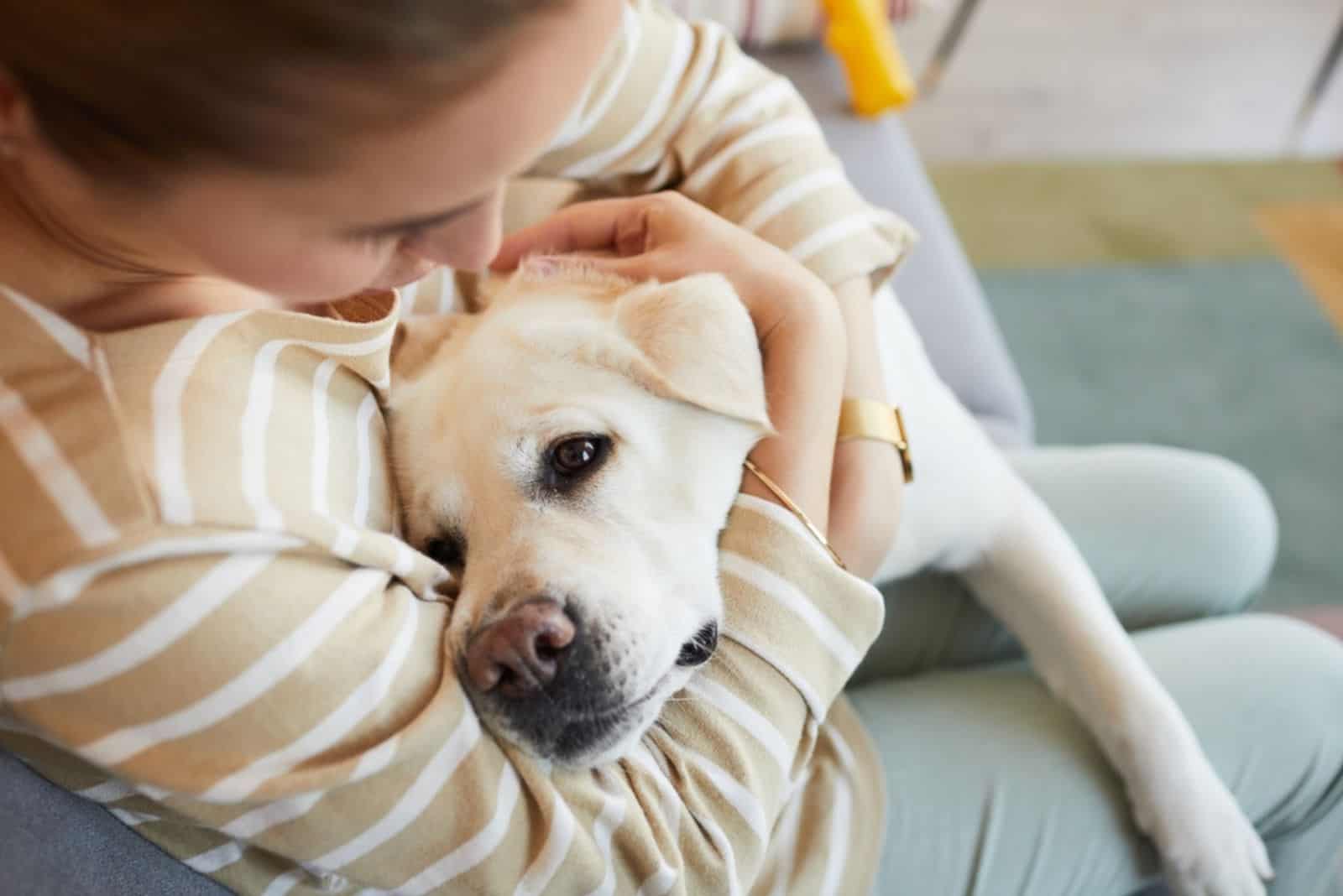 woman cuddling with white dog at home