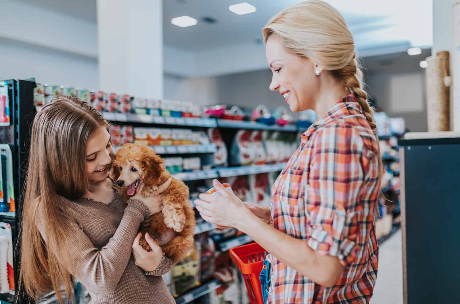 Mother and daughter with their poodle puppy in pet shop