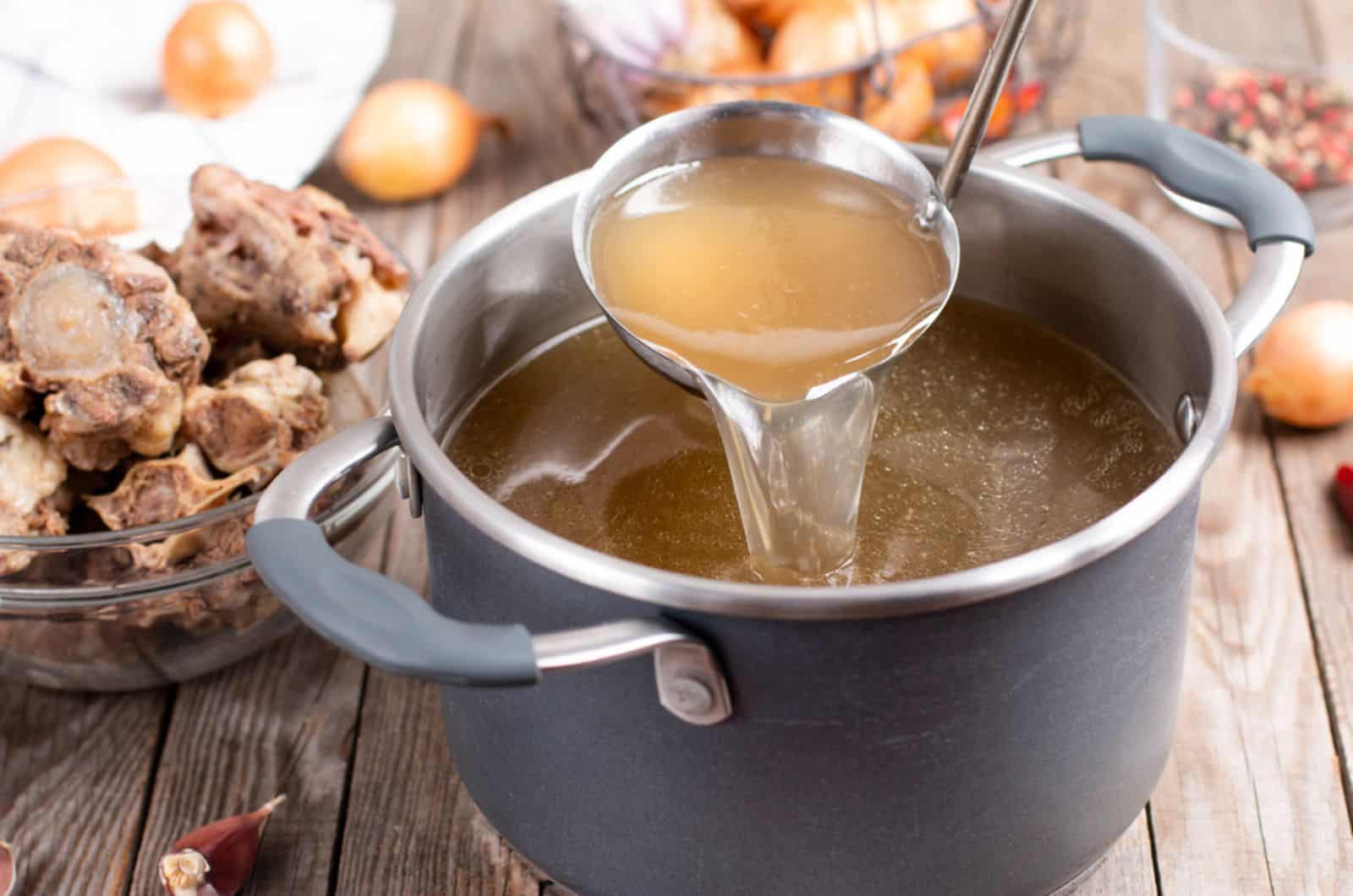 Saucepan with bouillon with a ladle on the table