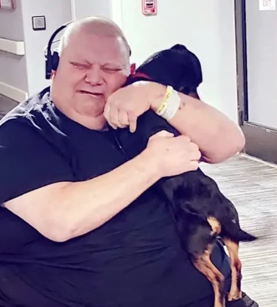 un hombre abraza a su perro y llora