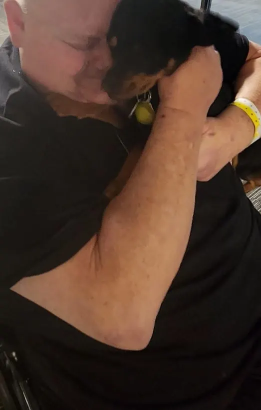 un hombre en silla de ruedas abraza a su perro