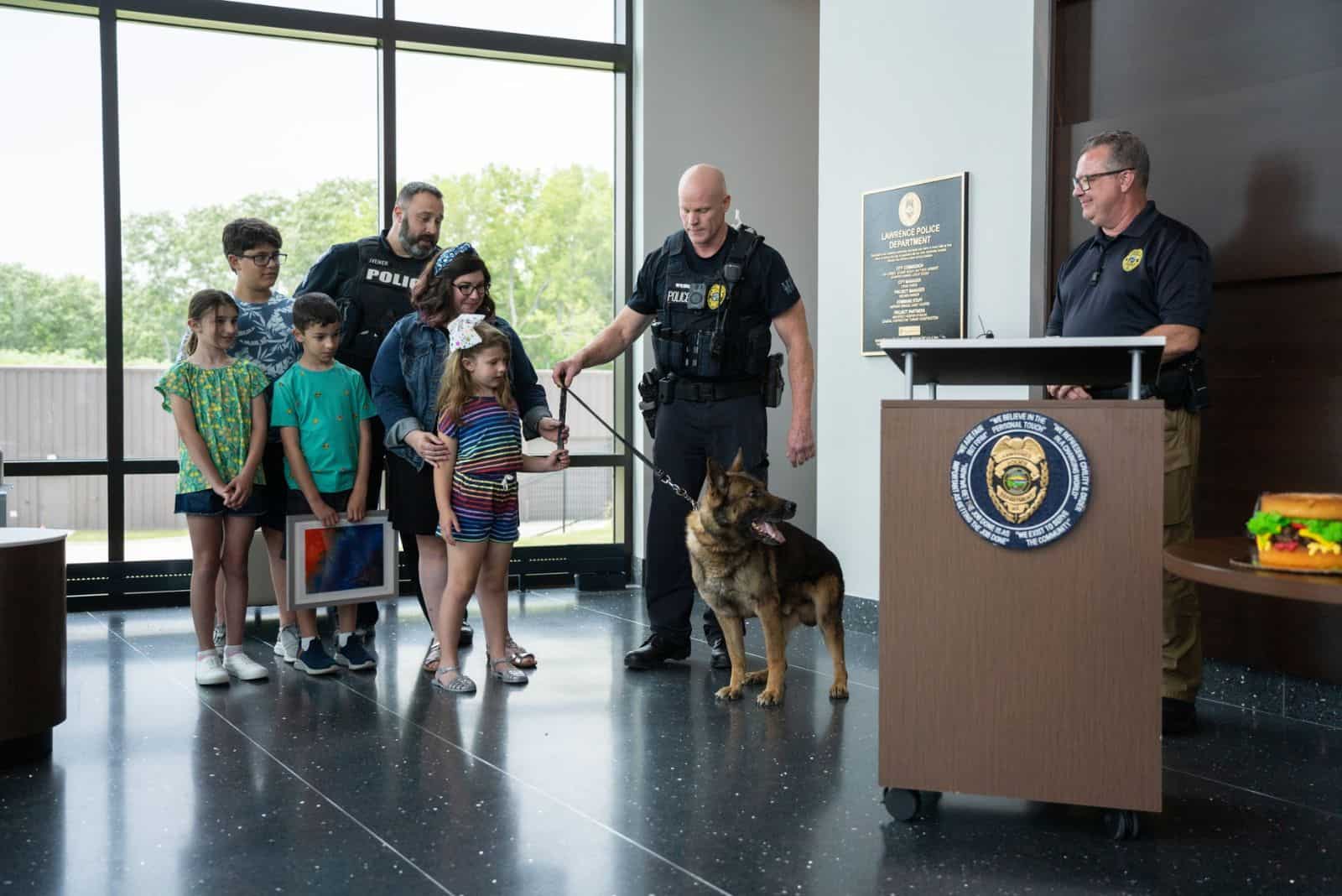 police officer holding german shepherd dog on a leash and giving him to his new family