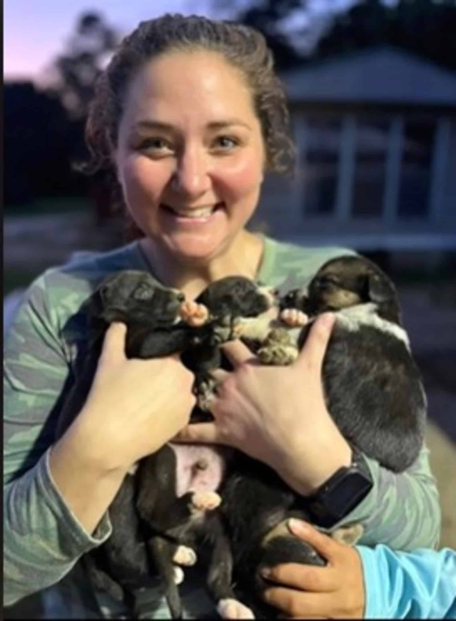 smiling woman holding puppies in her arms