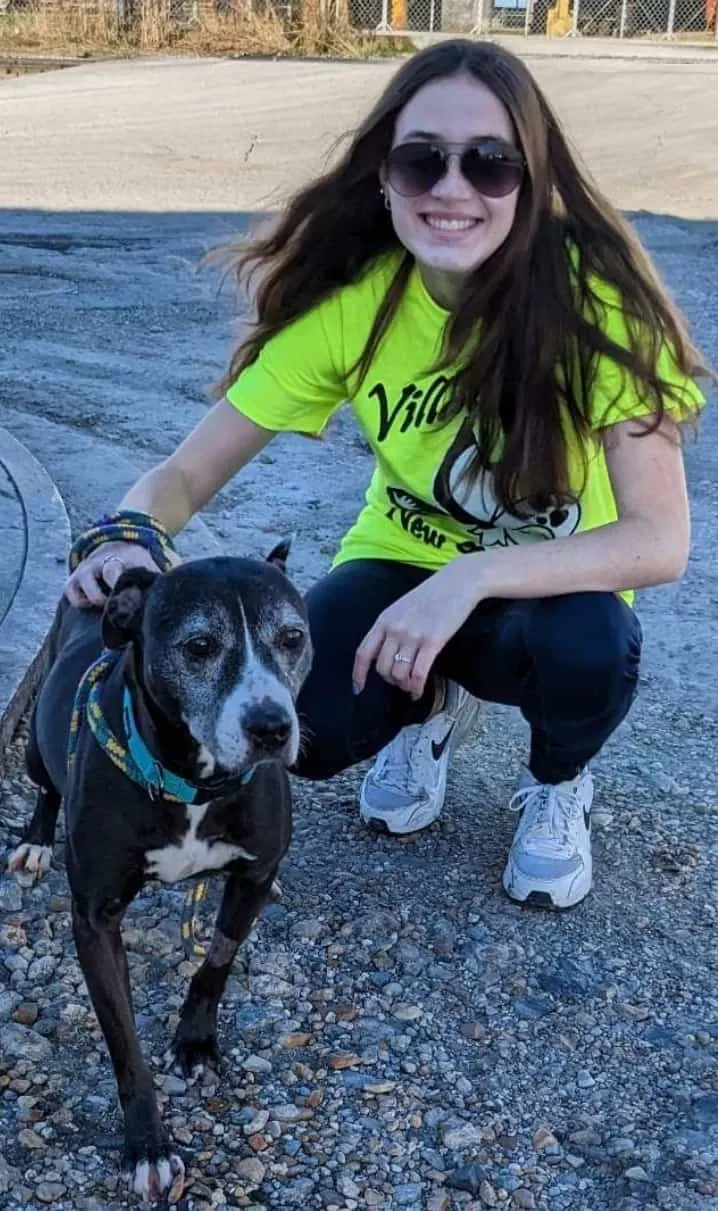 young girl in yellow shirt posing with dog and petting him