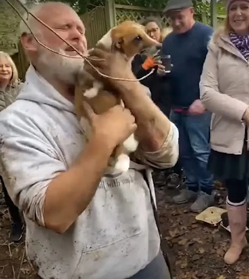 frantic owner crying while holding his dog in a crowd