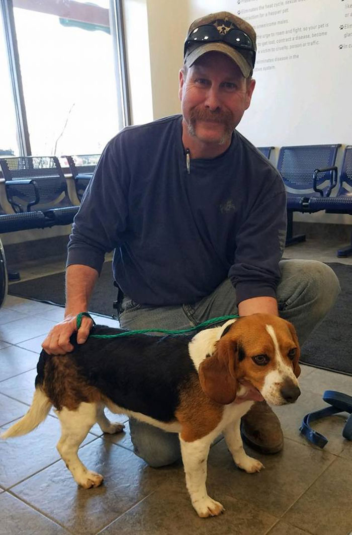 man kneeling next to a dog