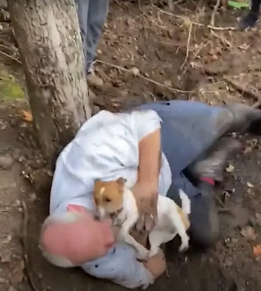 man lying on the ground holding the dog