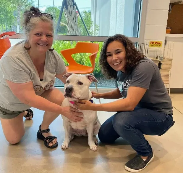 dos mujeres sonrientes se toman una foto con un perro blanco