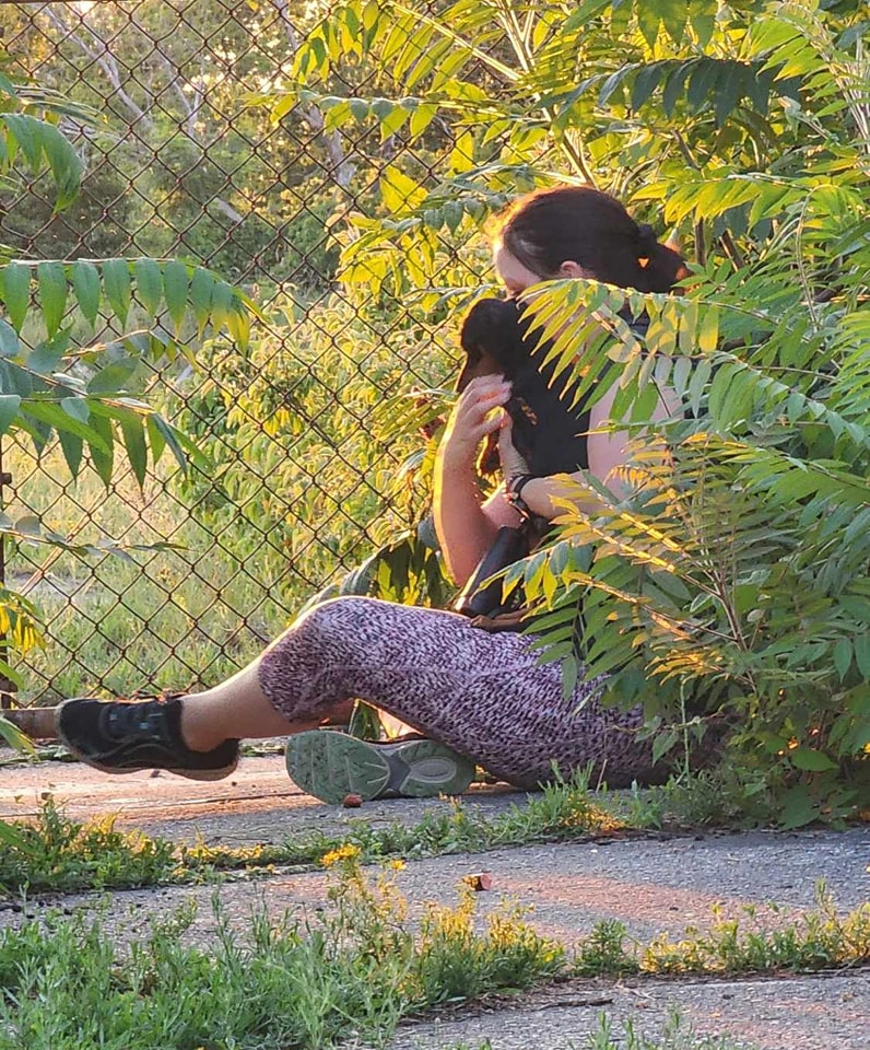 woman sitting on the ground and holding the dog