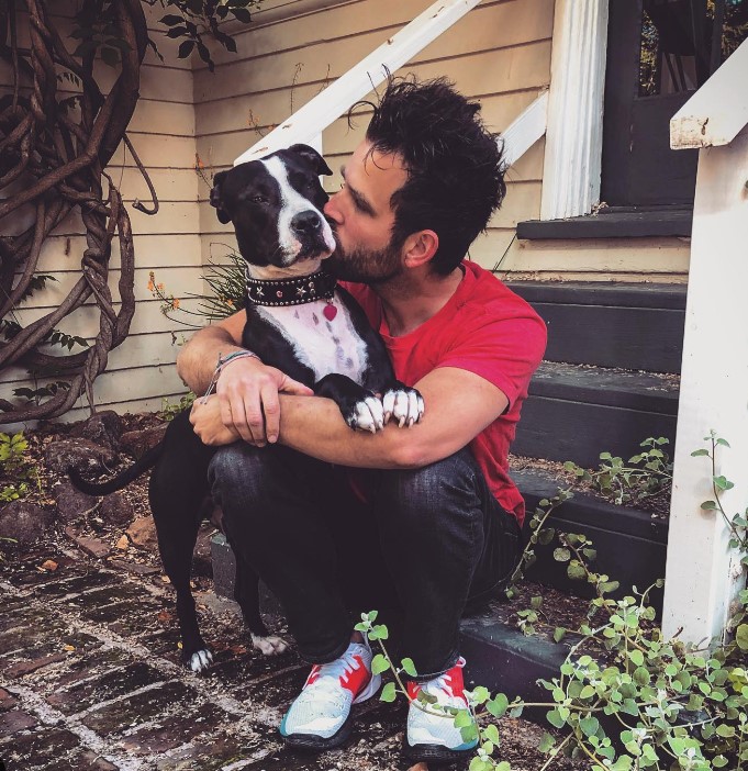 a man sits on the steps while kissing and hugging his dog