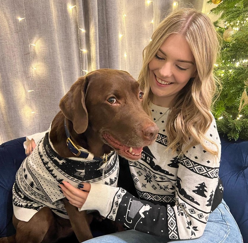 a smiling dog and a girl dressed alike sit next to each other