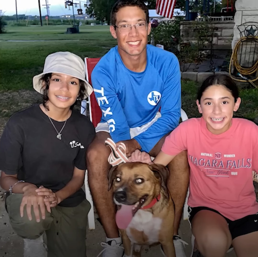 a smiling family takes a picture with a dog