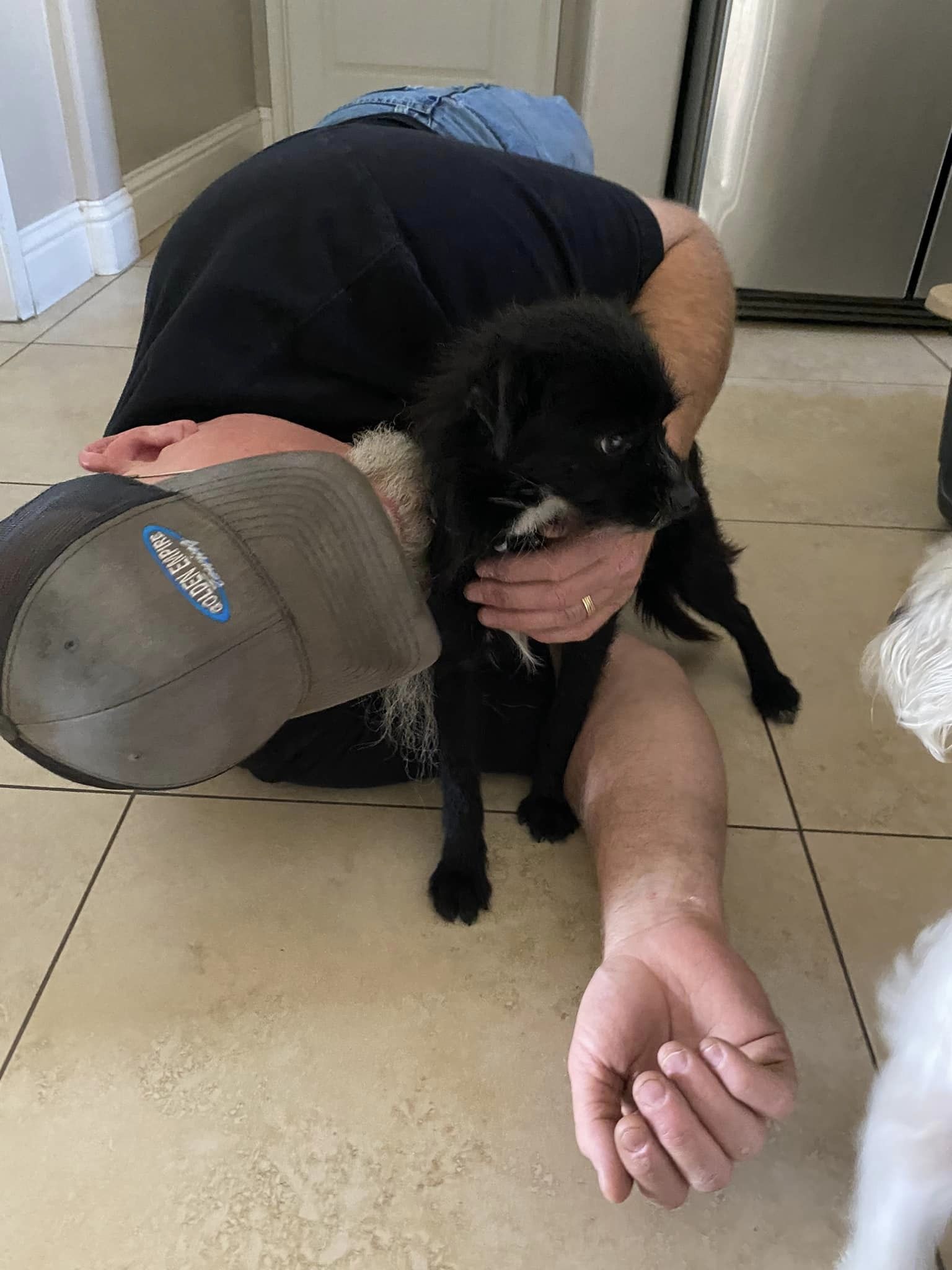 man hugging a tiny puppy while sitting on the floor