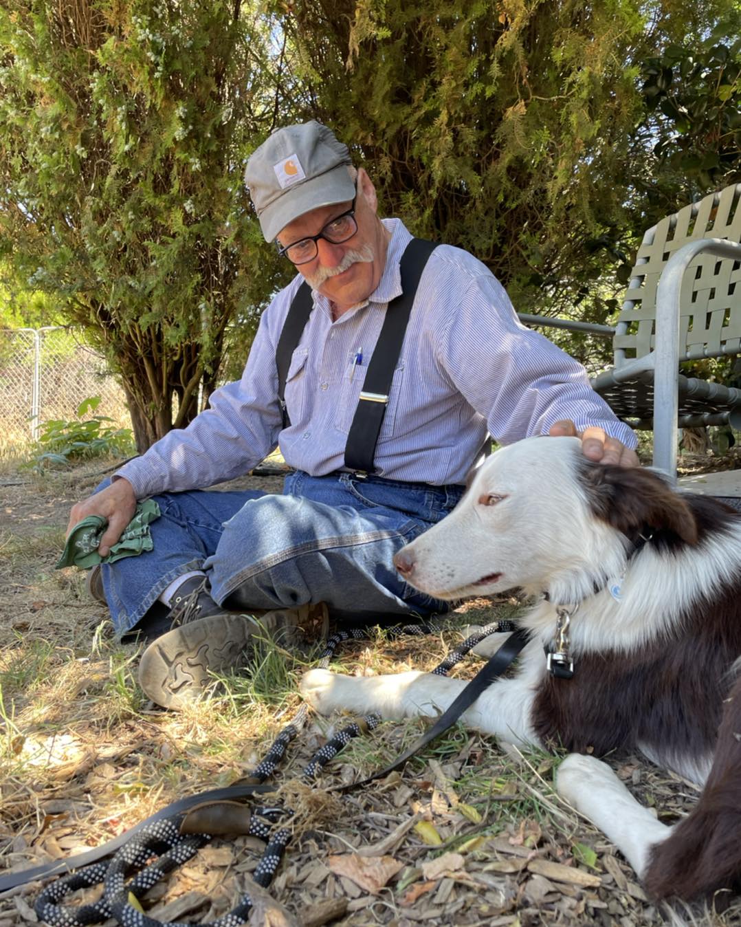 man sitting next to dog rocky and petting him