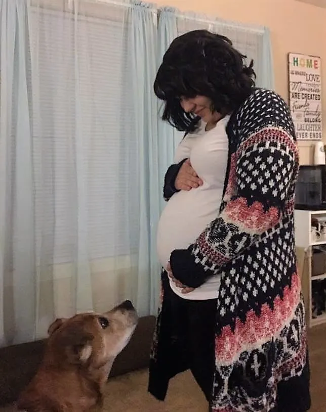 Pregnant woman holding her belly and senior dog looking at her