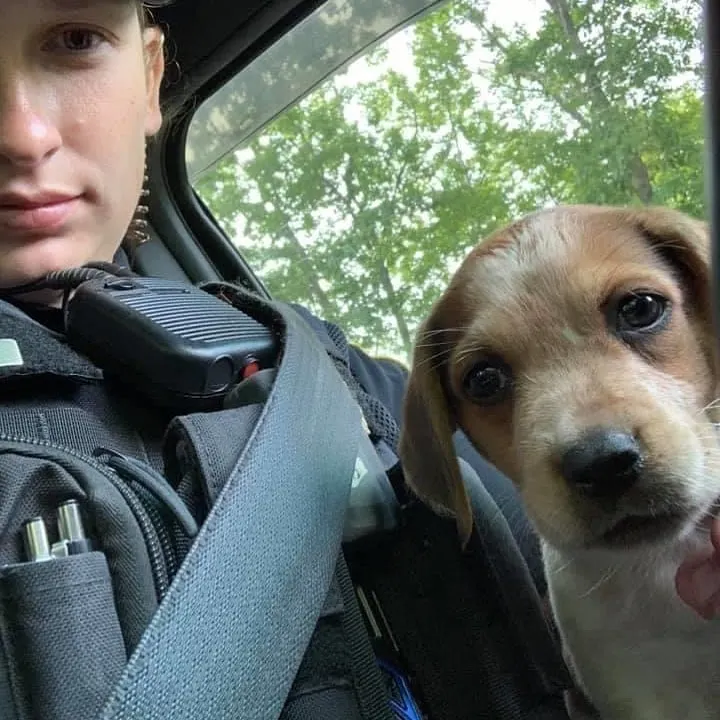 young police officer taking picture with dog