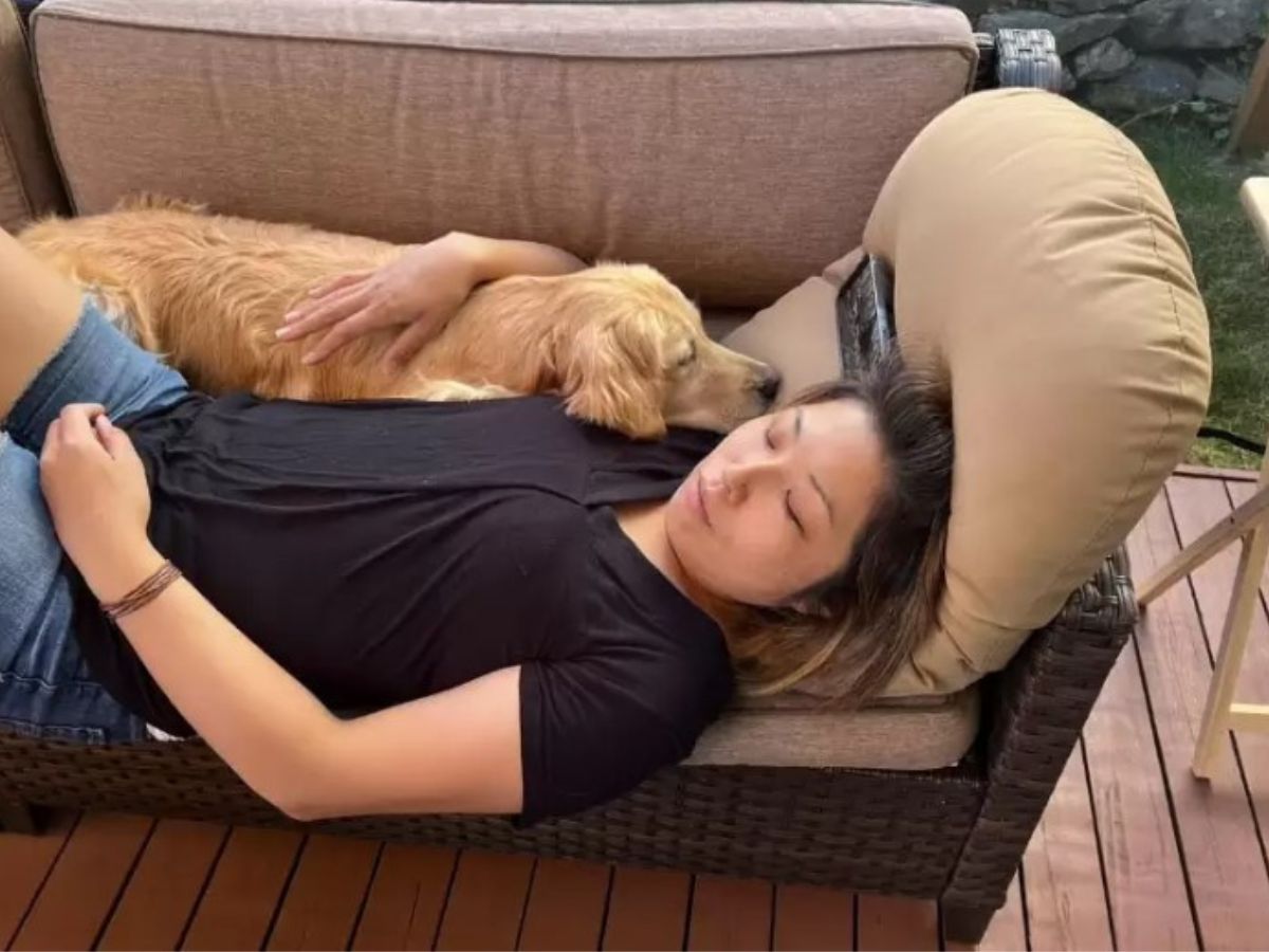Golden Pup sleeps next to a woman on a garden bench