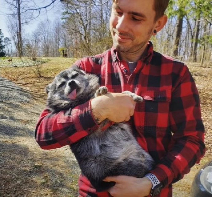 a man stands in the park and holds a dog in his arms