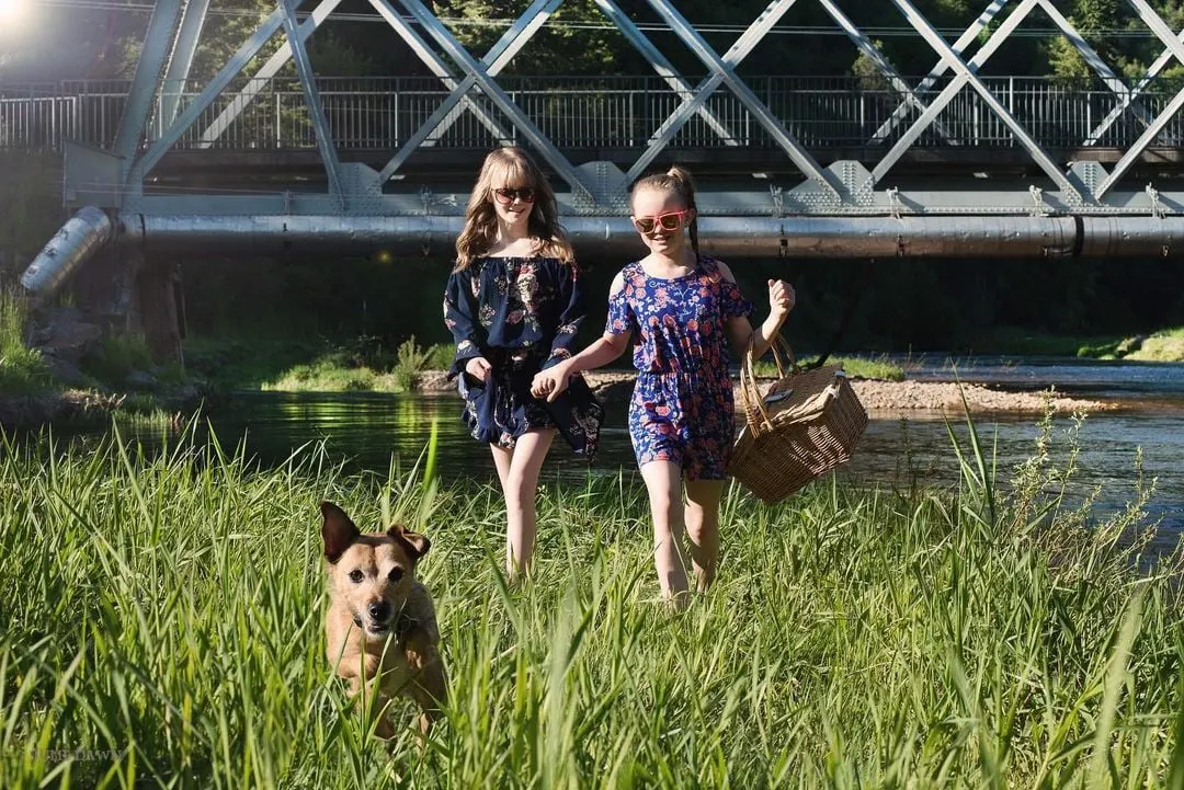 dog and two girls walking in grass
