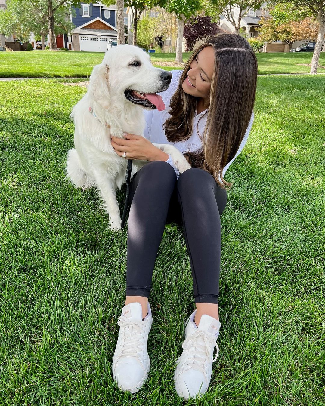 woman and golden retriever dog sitting on grass