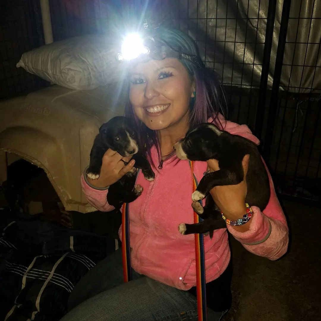 woman wearing headlamp holding two puppies
