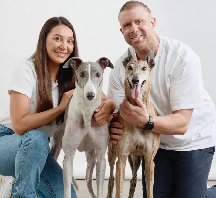 a man and a woman pose with their dogs
