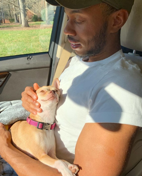 a man in a car exchanges affections with a chihuahua