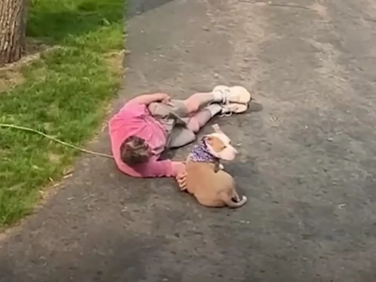 girl and dog laying together outside the house