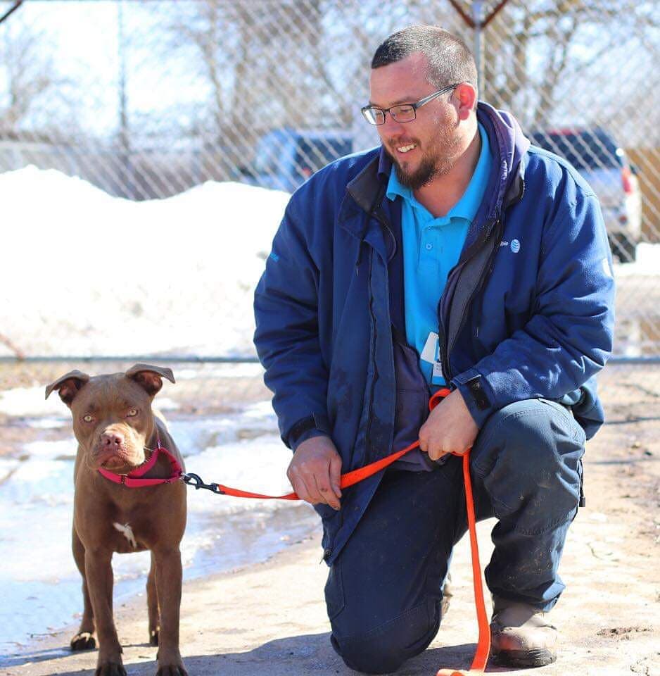man kneeling next to a dog on a leash
