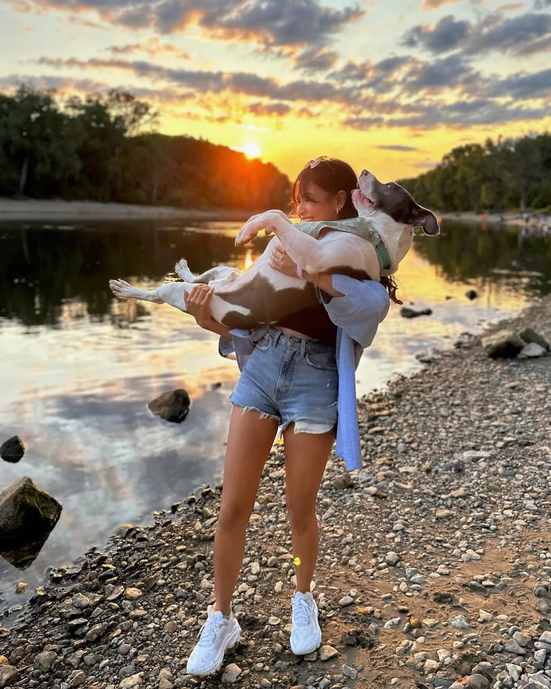 woman holding the dog at sunset