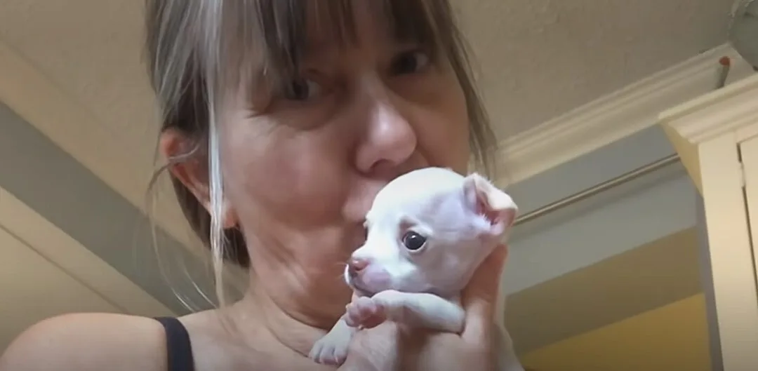 woman kissing her puppy