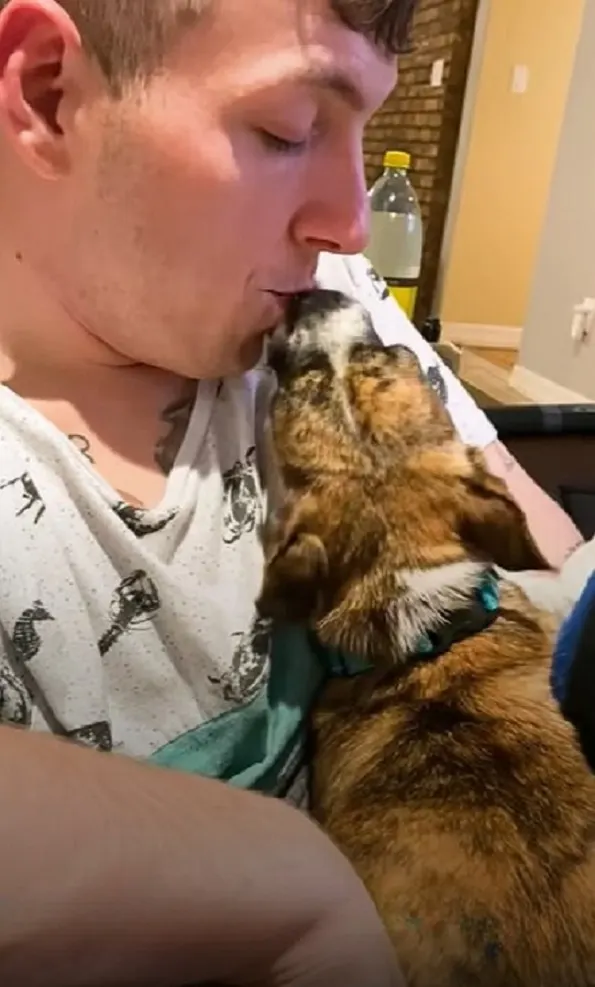 young man kissing dog