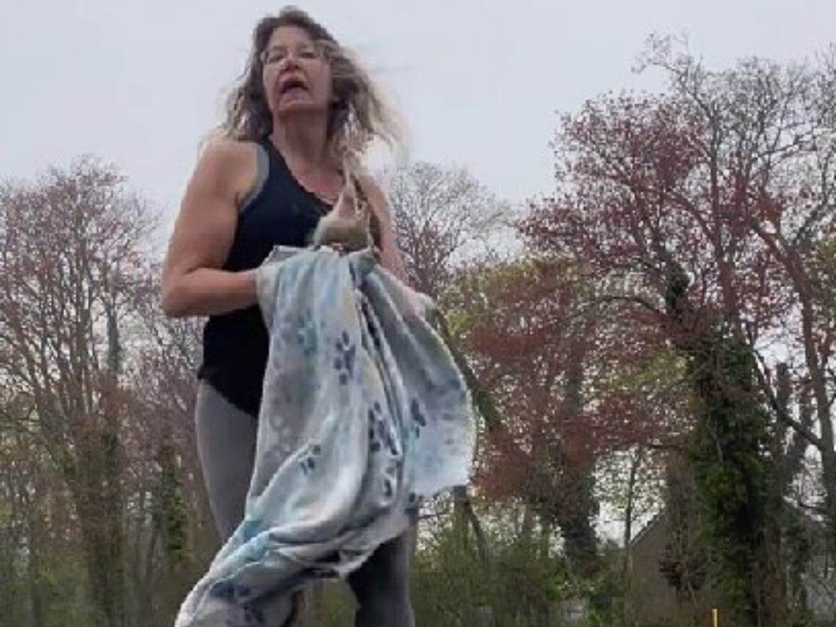 a woman carries a rescued wild animal wrapped in a blanket