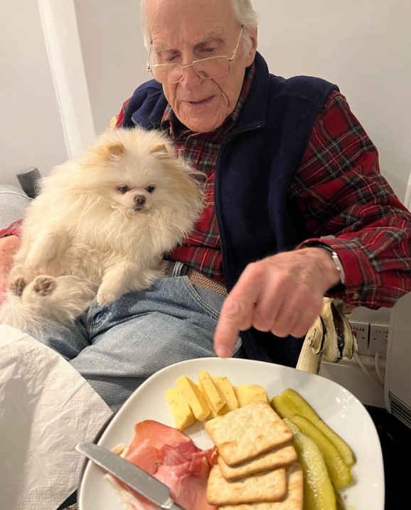 an elderly man eats a dog sitting on his lap