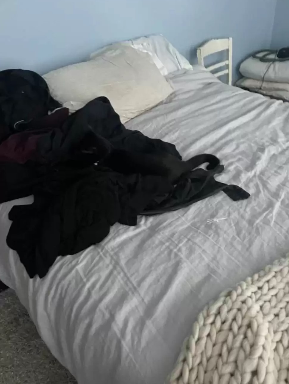 black cat with clothes on the bed