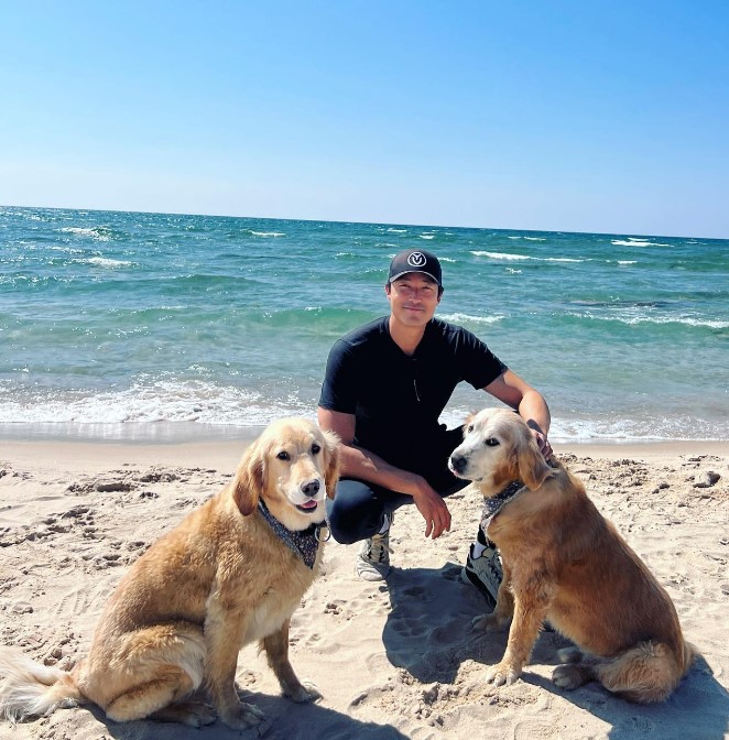 portrait of Actor Daniel Henney with two dogs on the beach