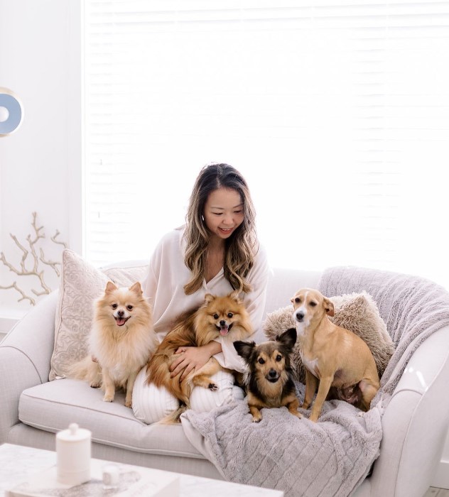 smiling woman sitting on couch with her adopted dogs