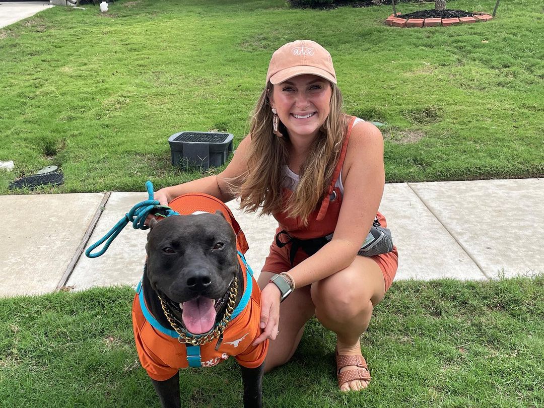 woman and black dog in orange clothes